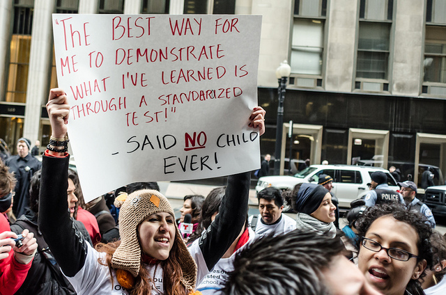 CHICAGO- 24 April, 2013: Demonstrator holds sign at a rally against school closings and over testing. (Photo: Sarah Jane Rhee)