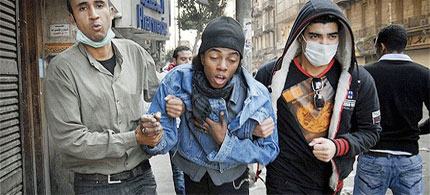 Two Egyptian protesters accompany a man, center, overcome with tear-gas inhalation during clashes with Egyptian riot police. (photo: AP)