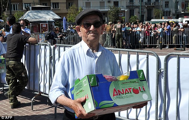 Despair: Pensioners joined the lengthy queues behind barriers in Athens where people were waiting for a free food handout