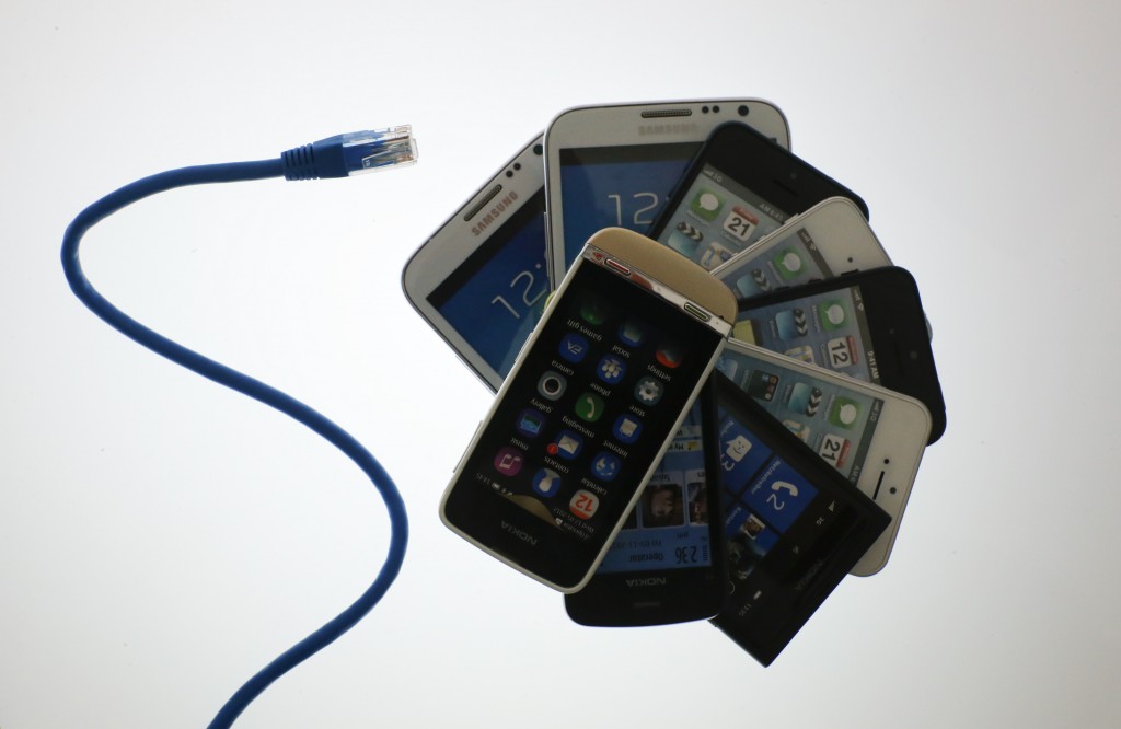 An illustration picture shows a network cable next to a pack of smartphones in Berlin